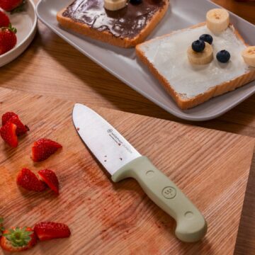 Ambiente con el cuchillo infantil Wüsthof Junior de color verde y fresas cortadas – Cuchillalia.com
